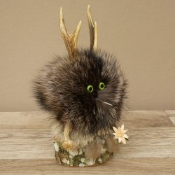Wolpertinger «Wolpi», modelo mini, sobre base de madera, con flor de las nieves y ojos verdes. Altura: 22 cm. 86.1.3.53